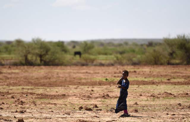 A young girl stands in a barren field, in Somaliland