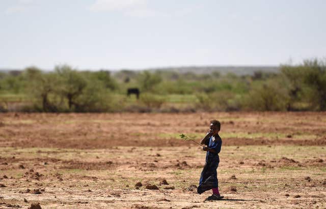 A young woman stands in an arid field in Somaliland. 