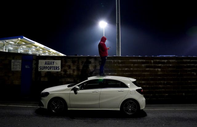A fan stands on top of a car to watch Barrow's FA Cup first round tie with AFC Wimbledon at Holker Street. With most post-lockdown games taking place behind closed doors, supporters have come up with novel ways to watch their teams, including using ladders and booking hotel rooms overlooking pitches. Home fans would have been disappointed on this occasion as Barrow were eliminated on penalties.
