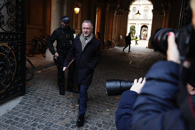 Photographers taking pictures of Steve Reed as he walks with a red Government folder under his arm