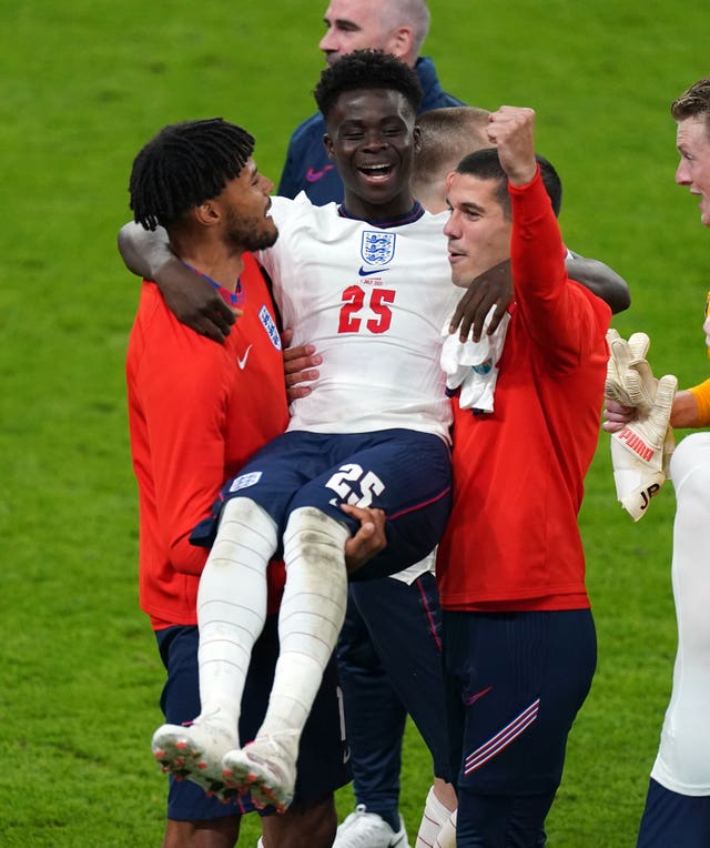 Tyrone Mings and Conor Coady carry Bukayo Saka as they celebrate victory over Denmark