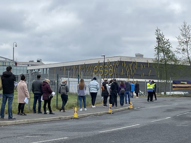 People queue for the vaccination centre at the Essa Academy in Bolton