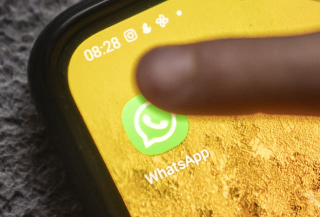 A child taps the WhatsApp app on a smartphone