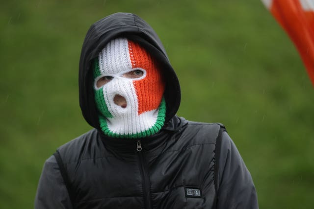 A person wearing a balaclava in the Irish flag colours
