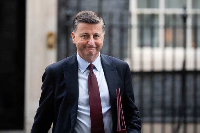 Douglas Alexander smiling while walking on Downing Street