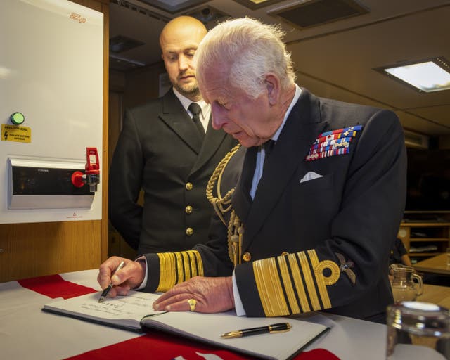 The King signing the visitors' book during a visit to the Royal Naval Armaments Depot Coulport