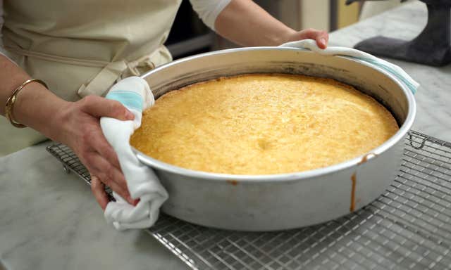 Claire Ptak carries part of the cake for the wedding of Harry and Meghan out of the oven in the kitchens at Buckingham Palace (Hannah McKay/PA)