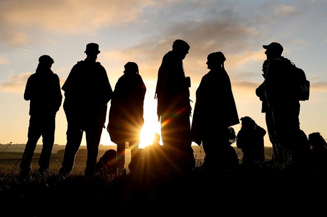 People watch the sun rise at the Avebury stone circle in Wiltshire