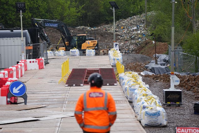 A person in hi vis watches as work with diggers is carried out to clear the waste site