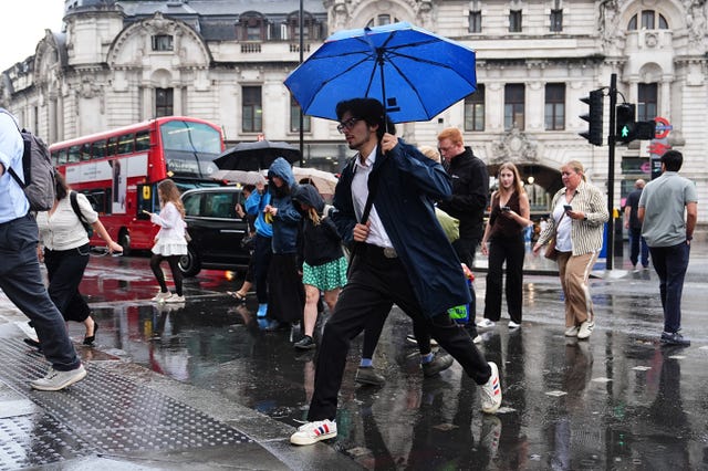 Man crossing road with blue umbrella