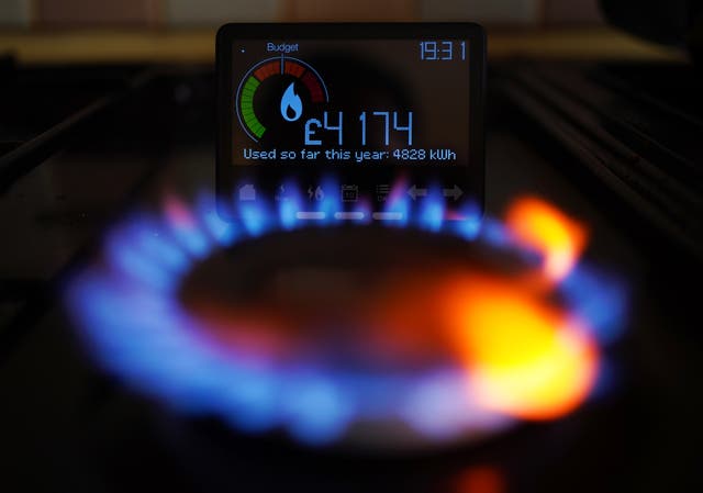 A lit gas hob in front of a smart energy meter