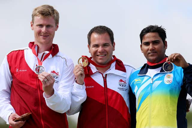 England's Steven Scott steps onto the podium to receive his gold medal following the Men's Double Trap, with silver medalist England's Matthew French (left) and bronze medalist India's Asab Mohd (right) at the 2014 Commonwealth Games