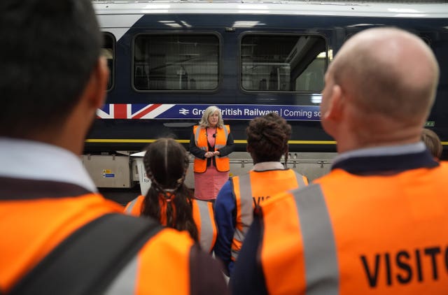People watching Heidi Alexander speak in front of a train with new branding