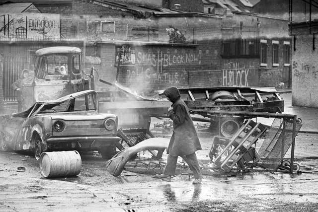 Burnt out vehicles litter the streets of the Falls Road area in Belfast during the Troubles