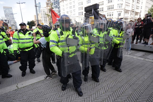 A group of riot police and other officers on a street, in high-vis jackets, helmets and holding shields