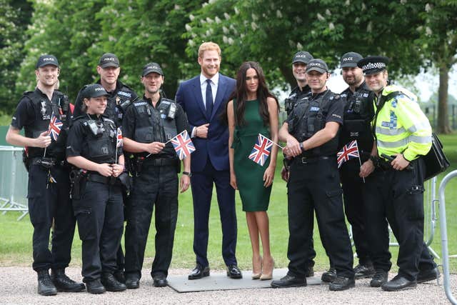 Police officers poses for photos with the Madame Tussauds' wax figures of Harry and Meghan (Jonathan Brady/PA)