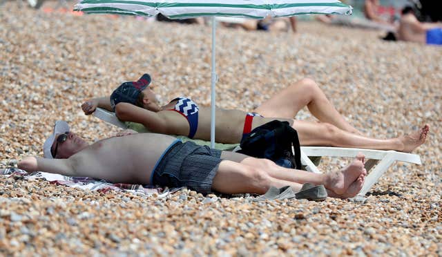 People enjoy the sunshine on Brighton beach as the warm weather continues across the country (Gareth Fuller/PA)