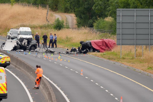 A red blanket draped over the remains of a badly damaged car