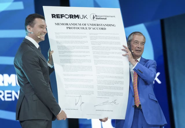Nigel Farage and Jordan Bardella hold up a signed memorandum of understanding
