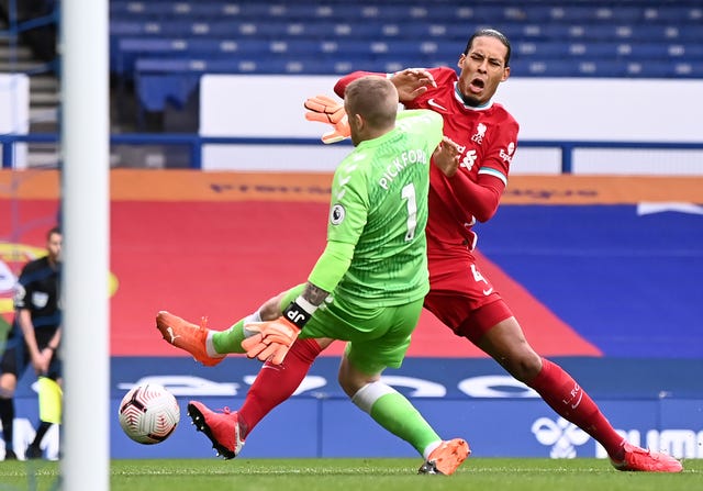 Virgil Van Dijk is tackled by Everton goalkeeper Jordan Pickford