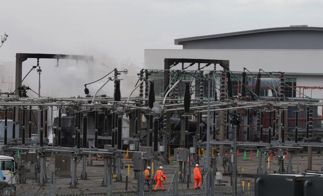 Workers in high-vis walk through the fire damaged substation