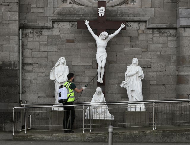 A man spraying disinfectant at a statue of the crucifixion of Jesus in Dublin on Good Friday.