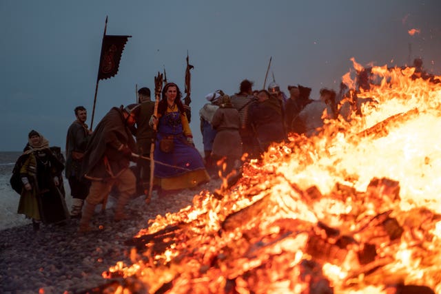 Re-enactors look on as a longboat burns