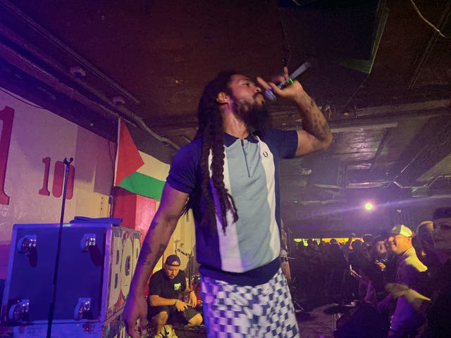 Bob Vylan performing on stage with a Palestine flag on display