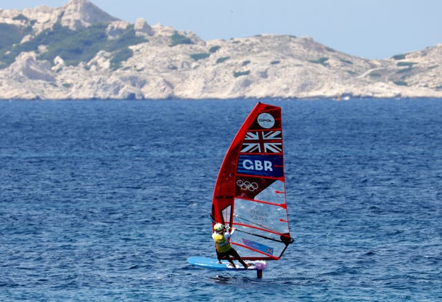 Great Britain’s Emma Wilson on her windsurfer with a GBR logo and mountains in the background.