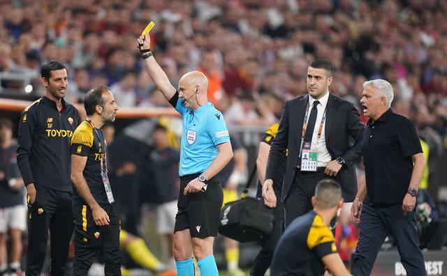 Anthony Taylor shows a yellow card to a member of Jose Mourinho's coaching staff