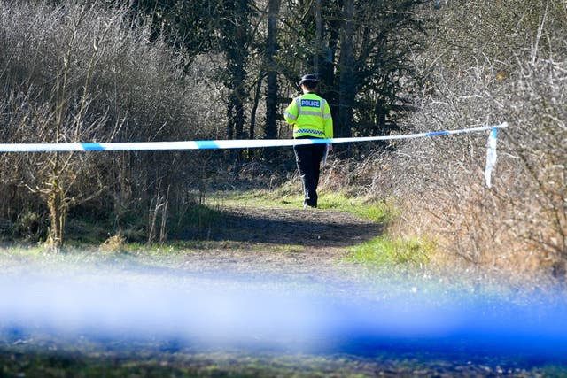 A police officer behind two police cordons in woodland at Pentylands Park, Highworth, where police are searching following a tip-off (Ben Birchall/PA)