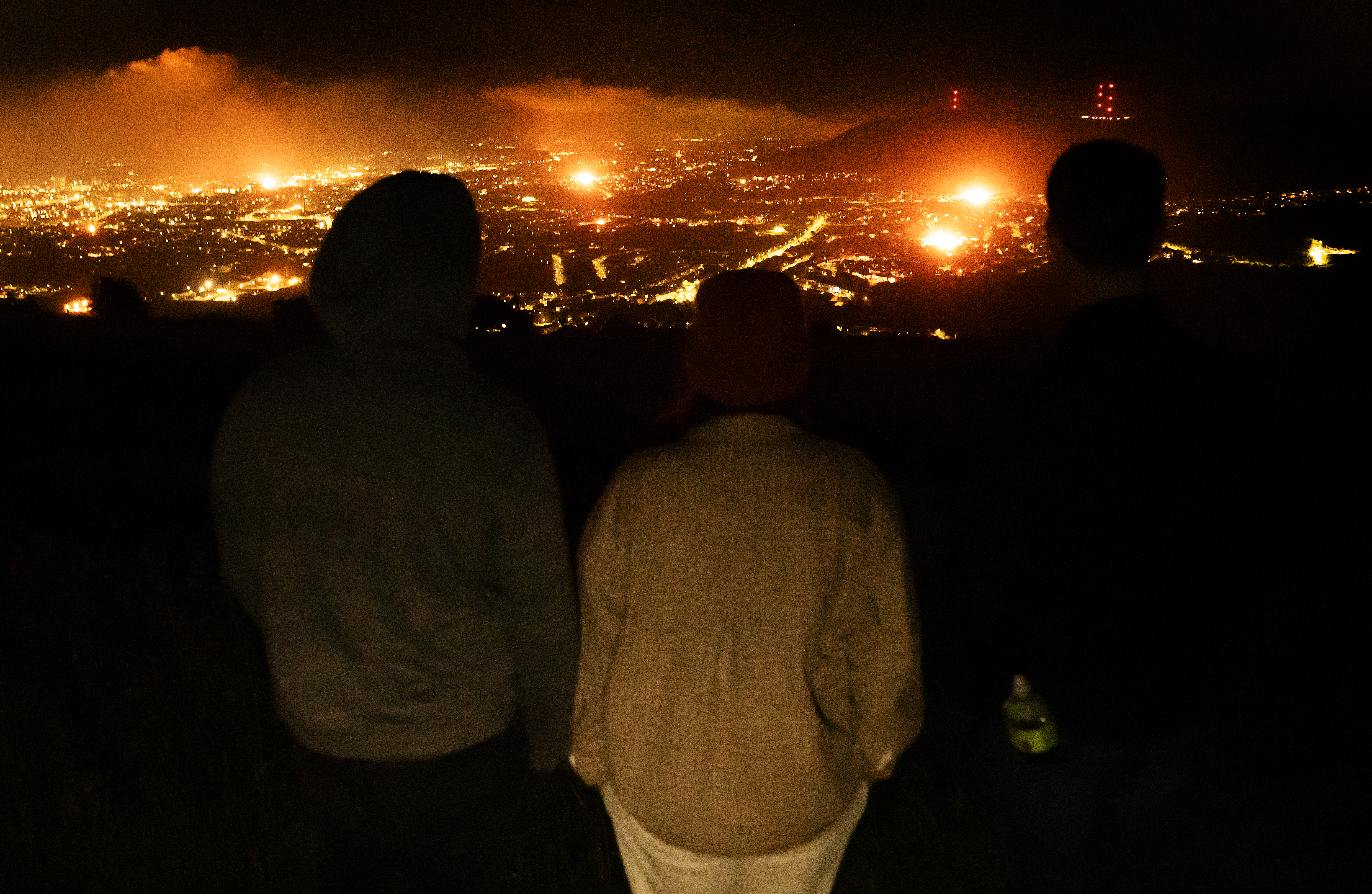 People looking out over Belfast as various bonfires burn