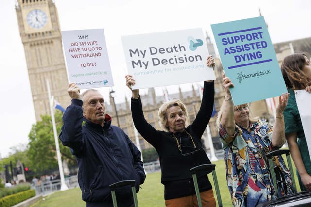 People stand in front of Big Ben holding signs. They read