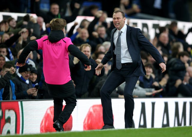 Ferguson celebrates with a ball boy after Everton score a third