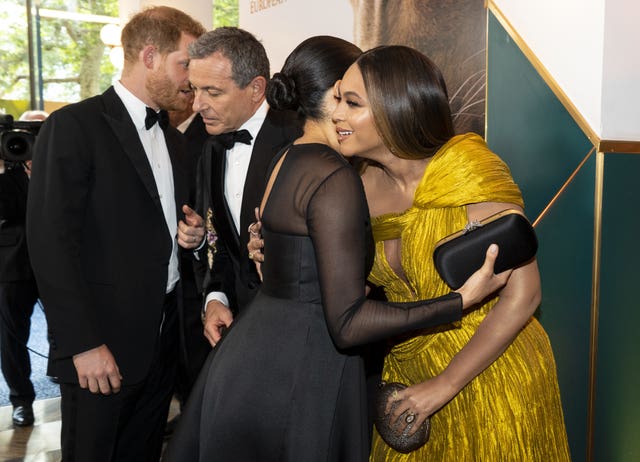 Beyonce and Meghan hugging, with the Duke of Sussex nearby