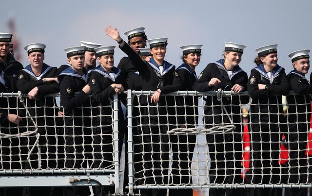 Crew members wave to the waiting crowd