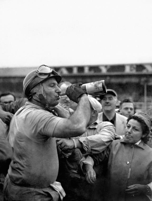 Argentinian Juan Fangio enjoys a well-earned drink after winning the British Grand Prix in a Ferrari in 1956