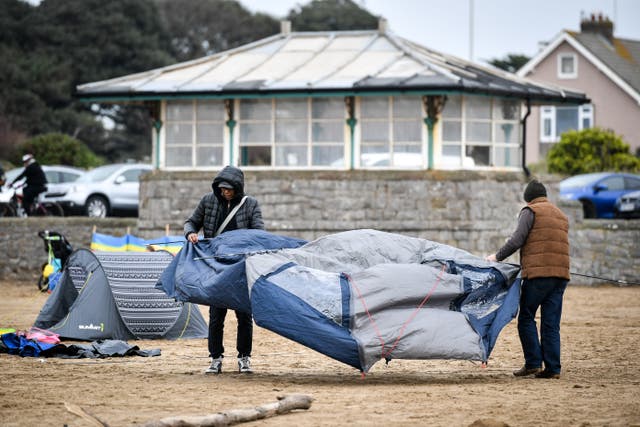People holding a tent on a beach
