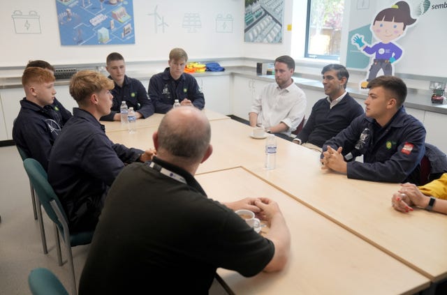 Rishi Sunak sitting at a large table with several students