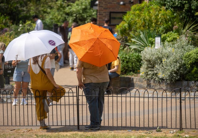 People shelter from the sun beneath umbrellas at St James’s Park in central London.