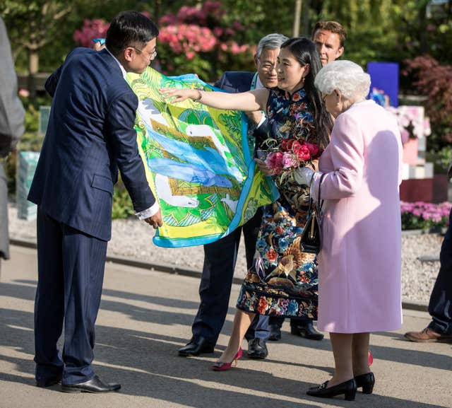 The Queen is presented with a Chinese silk scarf depicting two whales after she looked at the Chinese show garden (Richard Pohle/Times/PA)
