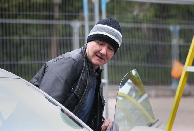 Irvine Welsh getting into a car, wearing a black leather jacket and hat