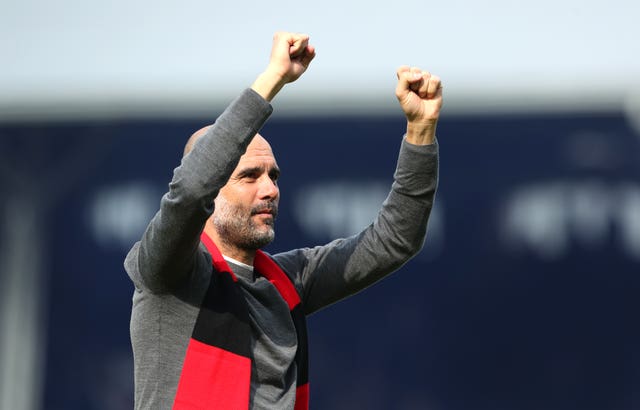Pep Guardiola celebrates in a red and black Manchester City scarf after victory over Fulham