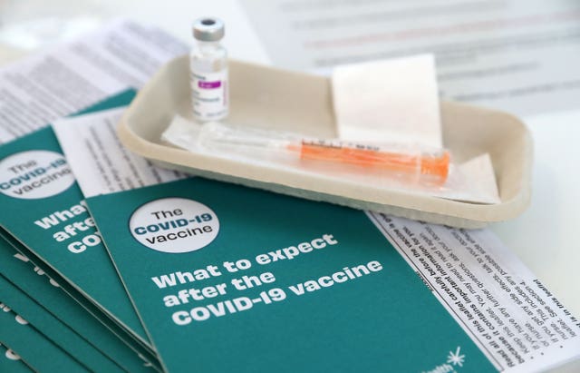 Covid-19 vaccine leaflets sit beside a vaccine vial (Andrew Milligan/PA)