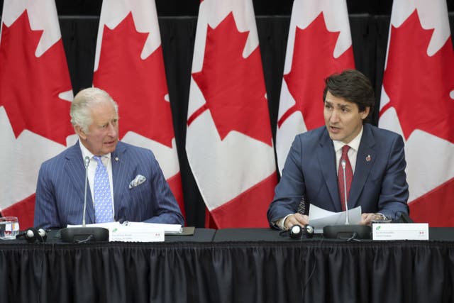 Charles as the Prince of Wales seated a table in front of a row of Canadian flags with Justin Trudeau in Ottawa, during his three-day trip to Canada in 2022