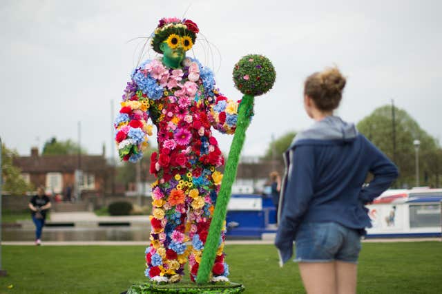 A young girl looks at British performer Flower Man (Aaron Chown/PA)