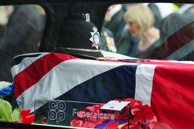 View of a Union Flag-draped coffin, with a police officer's hat on top