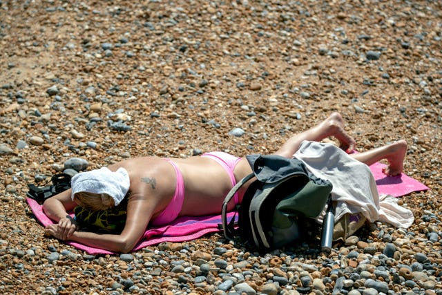 A woman sunbathes on Brighton beach (Steve Parsons/PA)