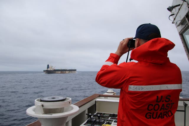 Handout photo taken from the X account of US European Command @US_EUCOM showing a member of the US Coast Guard observing a Venezuela-linked oil tanker which is travelling off British waters
