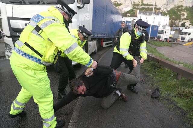 Police remove a man lying in the road in front a freight lorry as it tries to leave the Port of Dover